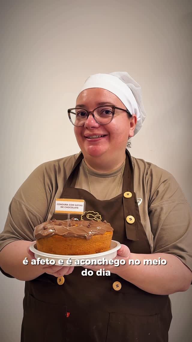 Confeiteira sorrindo com um bolo de cobertura clara nas mãos